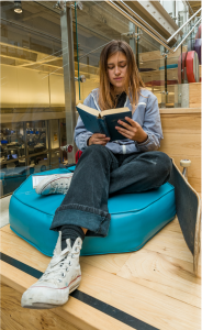 A student reading a book on the stairs of HLC