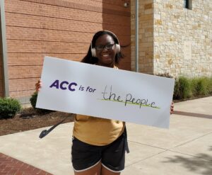 student holding sign saying "ACC is for the people"